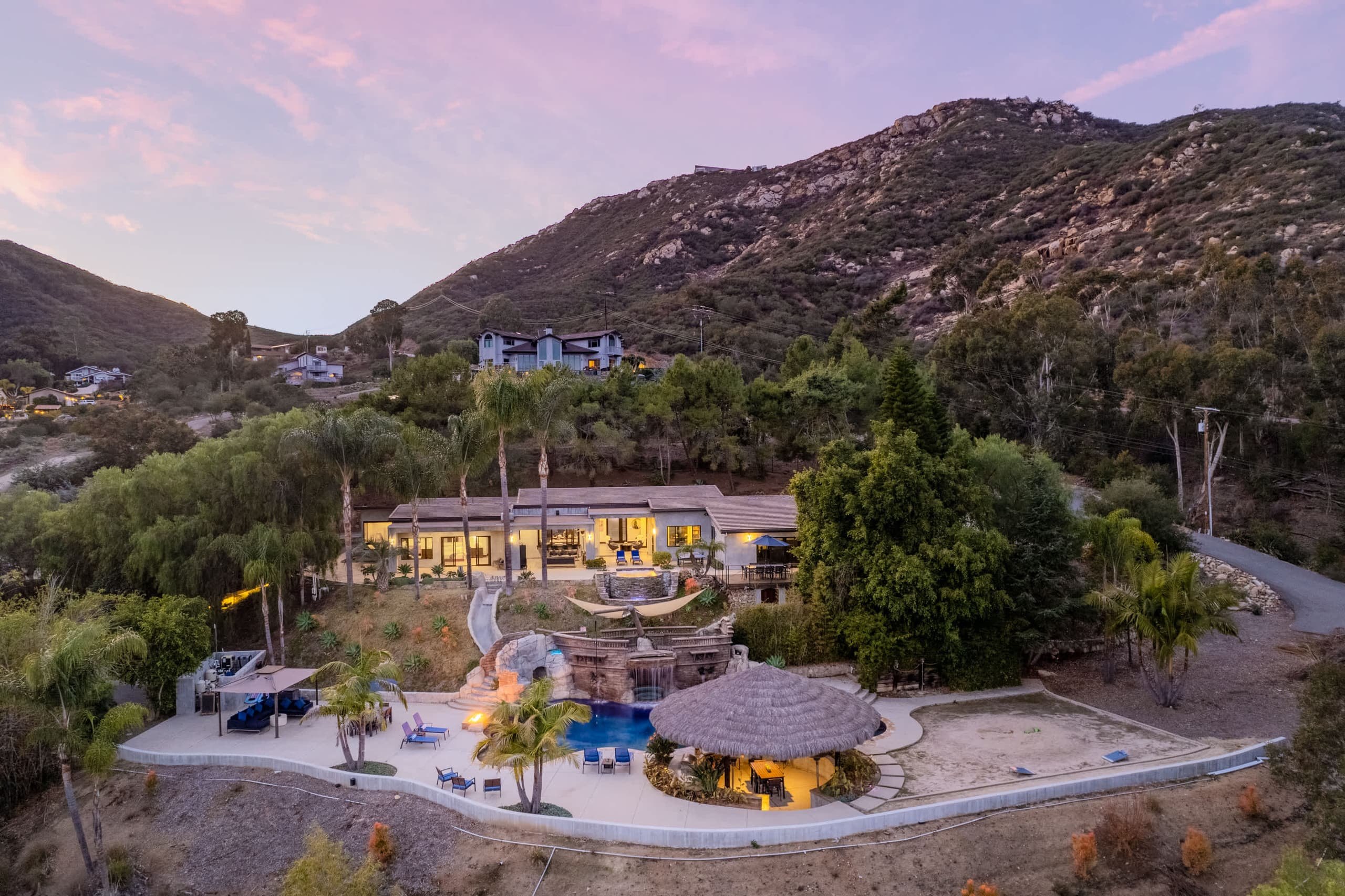 Aerial view at dusk of the estate on a hillside, pool and palapa in the foreground